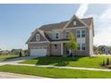 Beautiful two-story home with brick and siding, attached garage, green lawn and tree at 1101 Knoll Ct, Greenwood, IN 46143