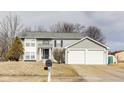Traditional two-story home featuring gray siding and a spacious two-car garage on a sunny day at 11410 Dunshire Dr, Indianapolis, IN 46229
