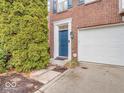Welcoming front entrance with a vibrant blue door, lush greenery, and a convenient attached garage at 11936 Esty Way, Carmel, IN 46033