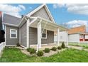 Beautifully landscaped home featuring a quaint front porch, gray siding, and well-manicured landscaping at 1804 Spann Ave, Indianapolis, IN 46203