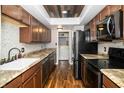 Open kitchen with modern appliances, wood cabinets, granite countertops, and wood-look flooring at 4264 Foxglove Trce, Indianapolis, IN 46237