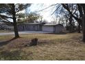 Single story home with attached garage, surrounded by trees and grass at 7144 Sandalwood Dr, Indianapolis, IN 46217