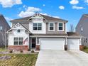 Charming two-story home with a three car garage, landscaped yard, and an American flag at 9264 Larson Dr, Pendleton, IN 46064