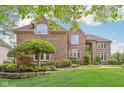 Charming brick home featuring an arched entryway, manicured lawn, and professionally landscaped yard at 13133 Brooks Landing Pl, Carmel, IN 46033
