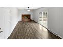Open-concept living room with sleek flooring, a brick fireplace, and backyard access at 1825 E 49Th St, Anderson, IN 46013