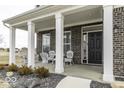 Inviting front porch featuring white columns, brick accents, and cozy seating, perfect for relaxing outdoors at 4078 Omaha Dr, Bargersville, IN 46106