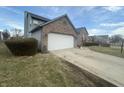 View of the house with attached garage, brick accents, and a well-maintained lawn on a partly cloudy day at 4418 Tarragon Dr, Indianapolis, IN 46237