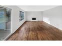 An empty living room is freshly painted with hardwood floors and features a fireplace and large windows at 7213 Shag Oak Dr, Noblesville, IN 46062