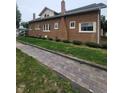Brick home showcasing a durable brick exterior, complemented by brick-paved sidewalks and manicured landscaping at 1001 S Anderson St, Elwood, IN 46036