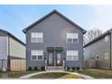 Front elevation of a charming two-story duplex with an inviting entrance, tidy front lawns, and gray siding at 139 Mckim Ave, Indianapolis, IN 46201