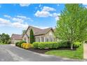 Charming stone home featuring manicured landscaping, a brick arch above the window, and lush green trees at 13902 Rue Royale Ln # 62, McCordsville, IN 46055