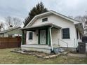 Charming home with green porch trim, security system, a tidy lawn, and steps to the front door at 3613 Schofield Ave, Indianapolis, IN 46218