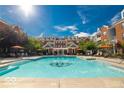 Community swimming pool with lounge chairs under orange umbrellas with brick townhouses in the background at 427 Windham Pass, Carmel, IN 46032