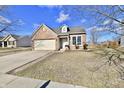 Inviting front exterior of a brick home with an attached garage, landscaped yard, and sunny curb appeal at 509 Yorktown Ln, Avon, IN 46123
