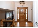 Bright foyer features hardwood floors, a statement light fixture, and a beautifully crafted wooden door at 5704 Springhollow Ct, Avon, IN 46123