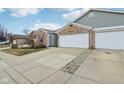 Long driveway leading to a two-car garage, with landscaping alongside the concrete at 7848 Cork Bend Ln, Indianapolis, IN 46239
