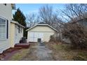 View of detached garage with white double doors and peeling yellow siding at 1228 E Perry St, Indianapolis, IN 46227