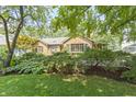 A well-maintained front yard featuring mature trees, lush greenery, and a brick home facade at 14 Kessler Blvd W Dr, Indianapolis, IN 46208