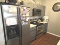 Well-lit kitchen with stainless steel appliances, gray cabinets, subway tile backsplash, and warm wood-look flooring at 2121 Grenville St # Apt 2A, Carmel, IN 46032