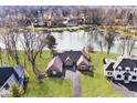 Aerial view of a waterfront home with well-manicured lawn, mature trees, and access to the water at 5519 Fall Creek Rd, Indianapolis, IN 46220