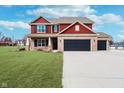 Inviting two-story home boasts brick and red siding, black shutters, and a wide driveway at 6880 W Jennifer Dr, Greenfield, IN 46140