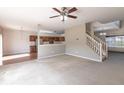 Open concept living room with a ceiling fan, and view of the kitchen and staircase at 11453 Scheel Ln, Carmel, IN 46032