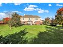 Expansive backyard with lush lawn, mature trees, and patio seating area at 11573 Westbury Pl Dr, Carmel, IN 46032