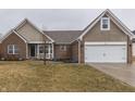 Exterior view of a home with brick and shake siding, attached garage, and a cozy front garden at 26 Downing Dr, Trafalgar, IN 46181