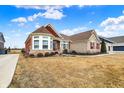 Beautiful single-story home featuring stone and red siding, complemented by lush green landscaping at 3924 Bear Creek Way, Carmel, IN 46074