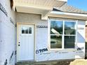 New construction home entrance featuring a white door, rectangular window, and materials to weatherproof the exterior at 614 Silver Fox Ct, Indianapolis, IN 46217