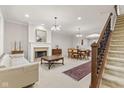 Traditional living room featuring a fireplace, staircase, and dining area at 6691 Beekman Pl, Zionsville, IN 46077