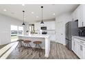 Bright kitchen featuring a kitchen island, modern lighting, stainless steel appliances, and wood-look flooring at 7156 Firestone Rd, Whitestown, IN 46052