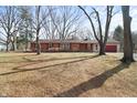 Cozy single-story brick home with a well-manicured lawn, mature trees, and an attached garage at 8615 El Rico Dr, Indianapolis, IN 46240
