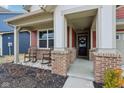 Charming front porch with brick supports and two rocking chairs flanking the front door with wreath at 1945 Clement St, Westfield, IN 46074