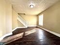 Inviting living room with original hardwood floors, staircase, and natural light streaming through the window at 2821 E 13Th St, Indianapolis, IN 46201