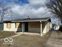 Exterior view of the damaged house, showing boarded windows, siding damage, and detached garage at 3458 Carr Ave, Indianapolis, IN 46221