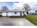 Charming one-story home features a front lawn, driveway, garage, and classic architecture under a cloudy sky at 8004 Minlo Dr, Indianapolis, IN 46227