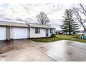 Charming one-story home features a front lawn, driveway, garage, and classic architecture under a cloudy sky at 8004 Minlo Dr, Indianapolis, IN 46227
