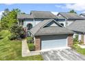 Two-story townhouse showcasing a brick-accented, front-facing garage, and a well-kept lawn at 8212 Nekton Ln, Indianapolis, IN 46236