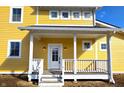 Close-up of a yellow home's charming front porch with white columns, railings, and an inviting front door at 10483 St Anne Dr, Zionsville, IN 46077