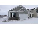 Charming gray home with a white garage door, black shutters, and brick accents nestled on a snow-covered lawn at 1841 James Pierce Dr, Shelbyville, IN 46176