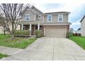 Charming two-story home with brick and beige siding, a covered porch, and an attached two-car garage at 2336 Boneset Dr, Plainfield, IN 46168
