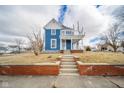 Charming two-story blue home featuring a welcoming front porch and brick-lined stairway at 300 E North Main St, Summitville, IN 46070