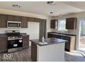 Well-lit kitchen with stainless steel appliances, dark countertops, and an island at 3825 Windstar Way, Columbus, IN 47203
