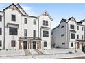 Charming two-story townhomes featuring a modern farmhouse design, black trim and snowy ground at 7070 Nine Penny Dr, Brownsburg, IN 46112