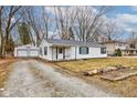 Charming one-story home featuring black window frames and a detached garage with a gravel driveway at 9909 N 125 W, Fortville, IN 46040