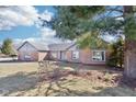 A well-maintained brick home with a spacious front yard under a blue sky with scattered clouds at 10709 E County Road 100 N, Indianapolis, IN 46234