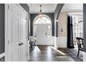 Inviting foyer with wood floors, neutral walls, wainscoting, and a statement chandelier hanging above the front door at 10896 Fairwoods Dr, Fishers, IN 46037