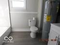 A simple bathroom with a toilet, a sink, and a water heater at 1311 E Hines St, Muncie, IN 47303