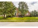 Beautiful brick home with lush green lawn and mature trees lining the street at 14297 Matt St, Carmel, IN 46033